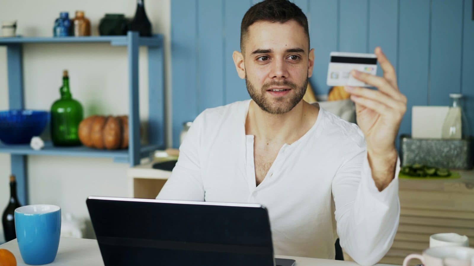 A shopper holding a credit card while looking at a laptop to complete an online order