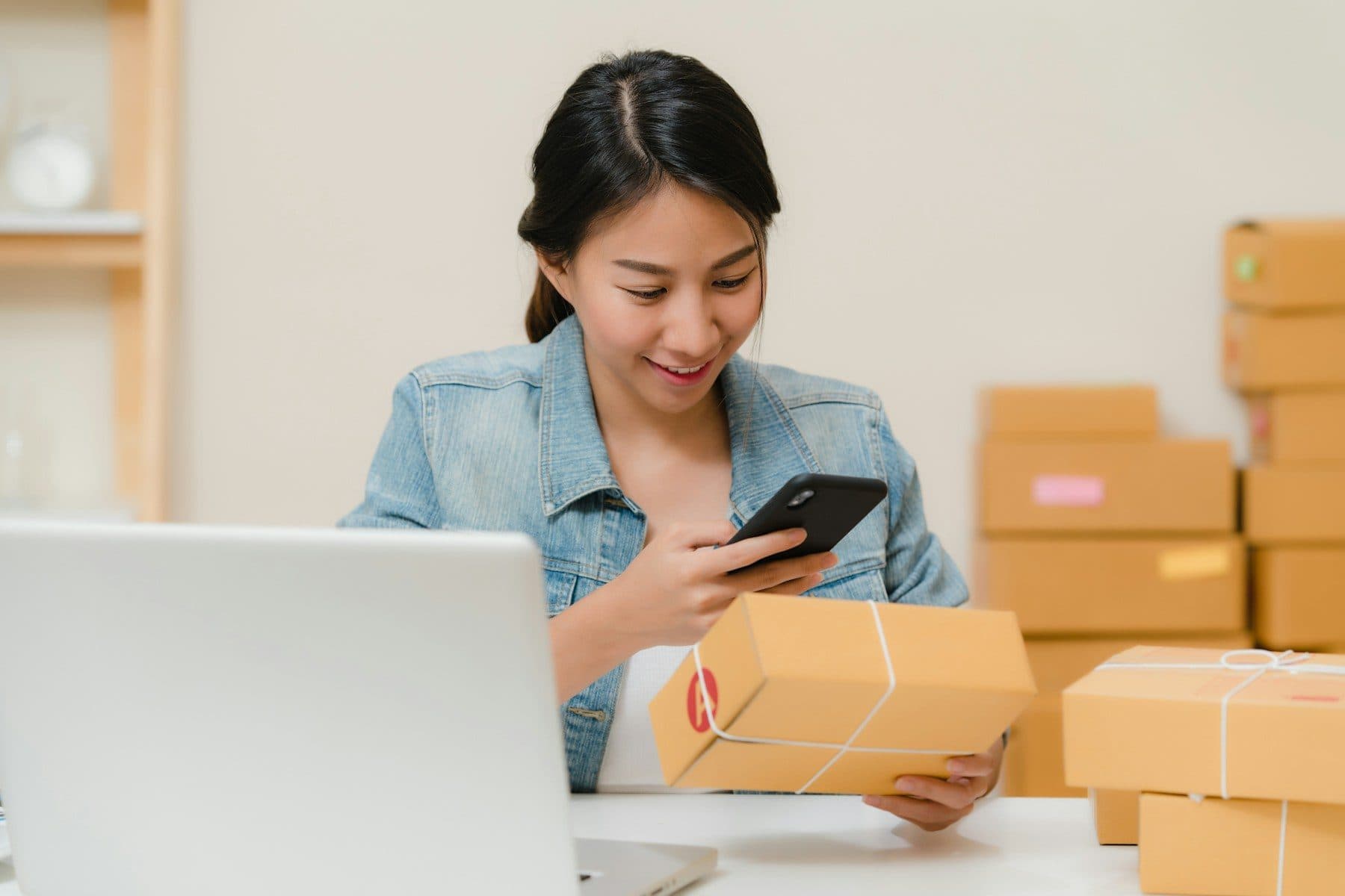 Online seller checking a parcel next to a laptop